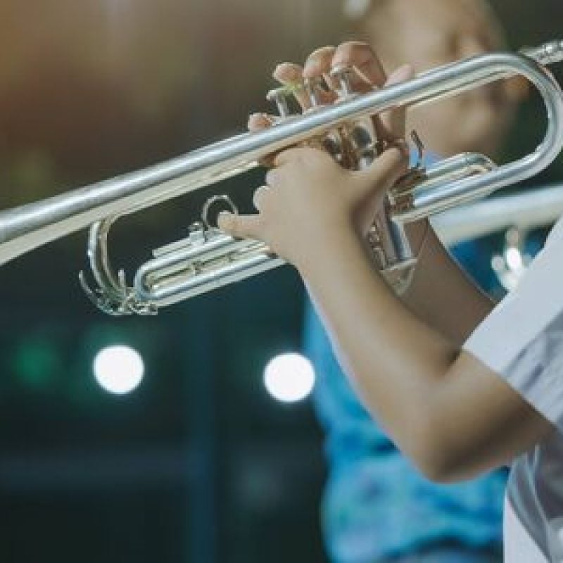 147081603-studente-maschio-con-amici-suona-la-tromba-con-la-band-per-l-esibizione-sul-palco-di-notte